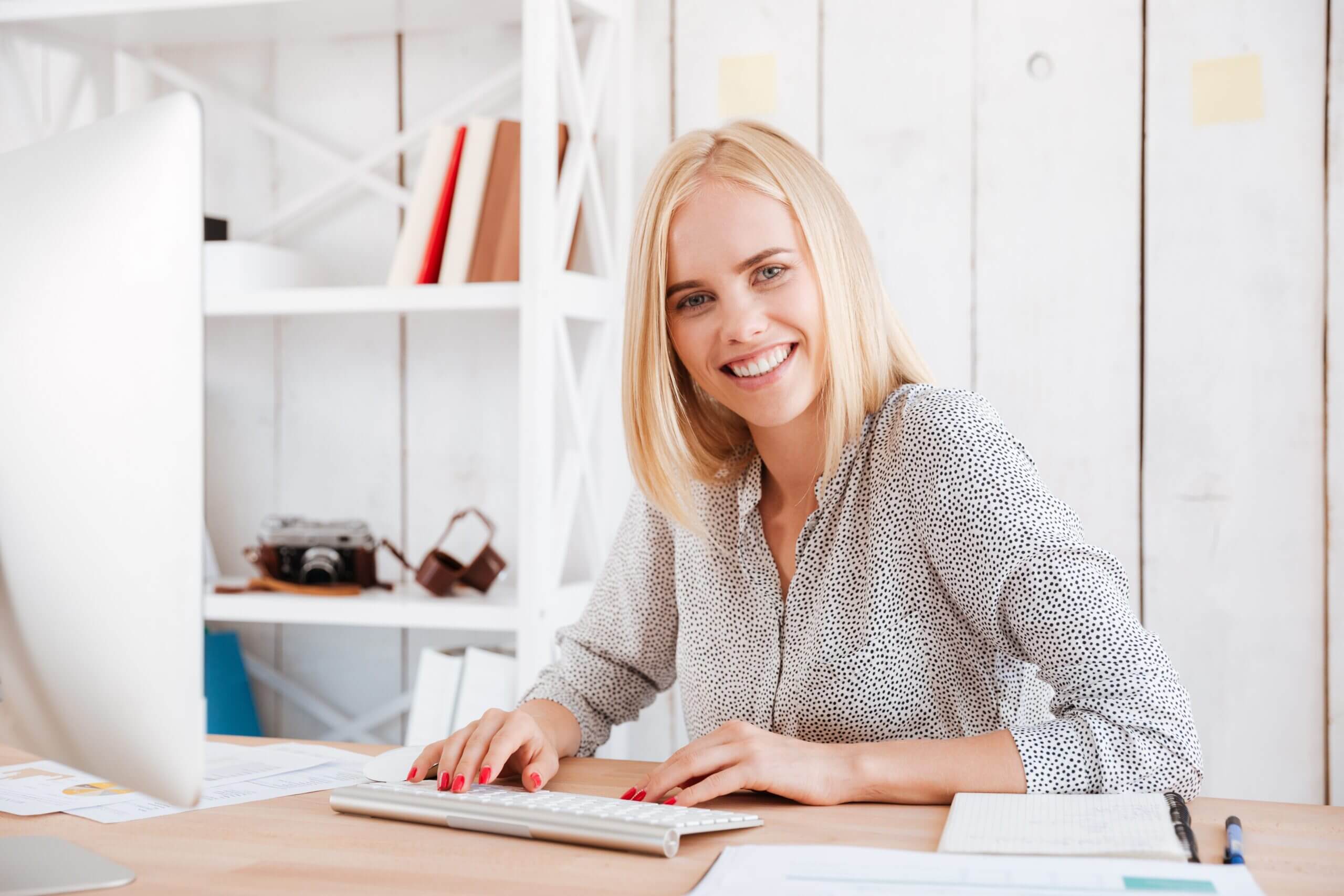 Portrait of a happy young business woman sitting with computer